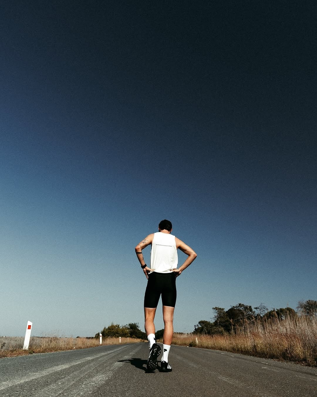 A runner stopped on the road, hands on hips